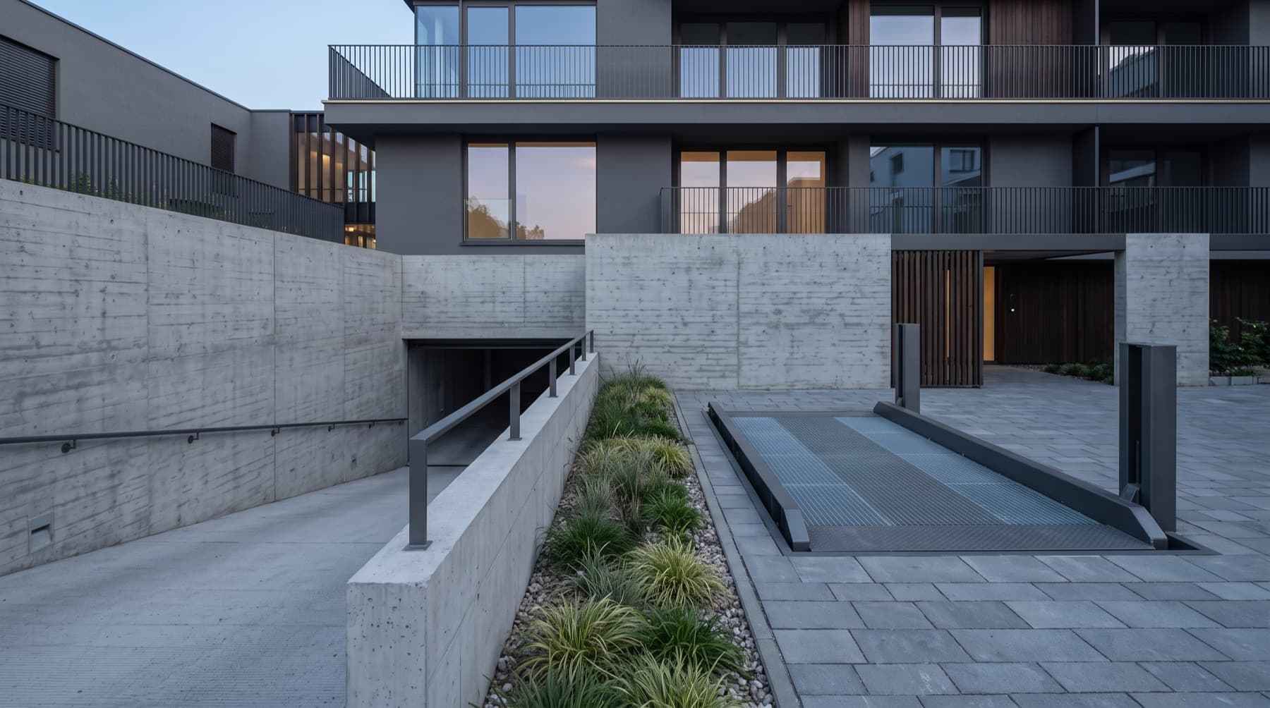 Cour d'un immeuble collectif, rampe béton et plateforme élévatrice affleurant le dallage