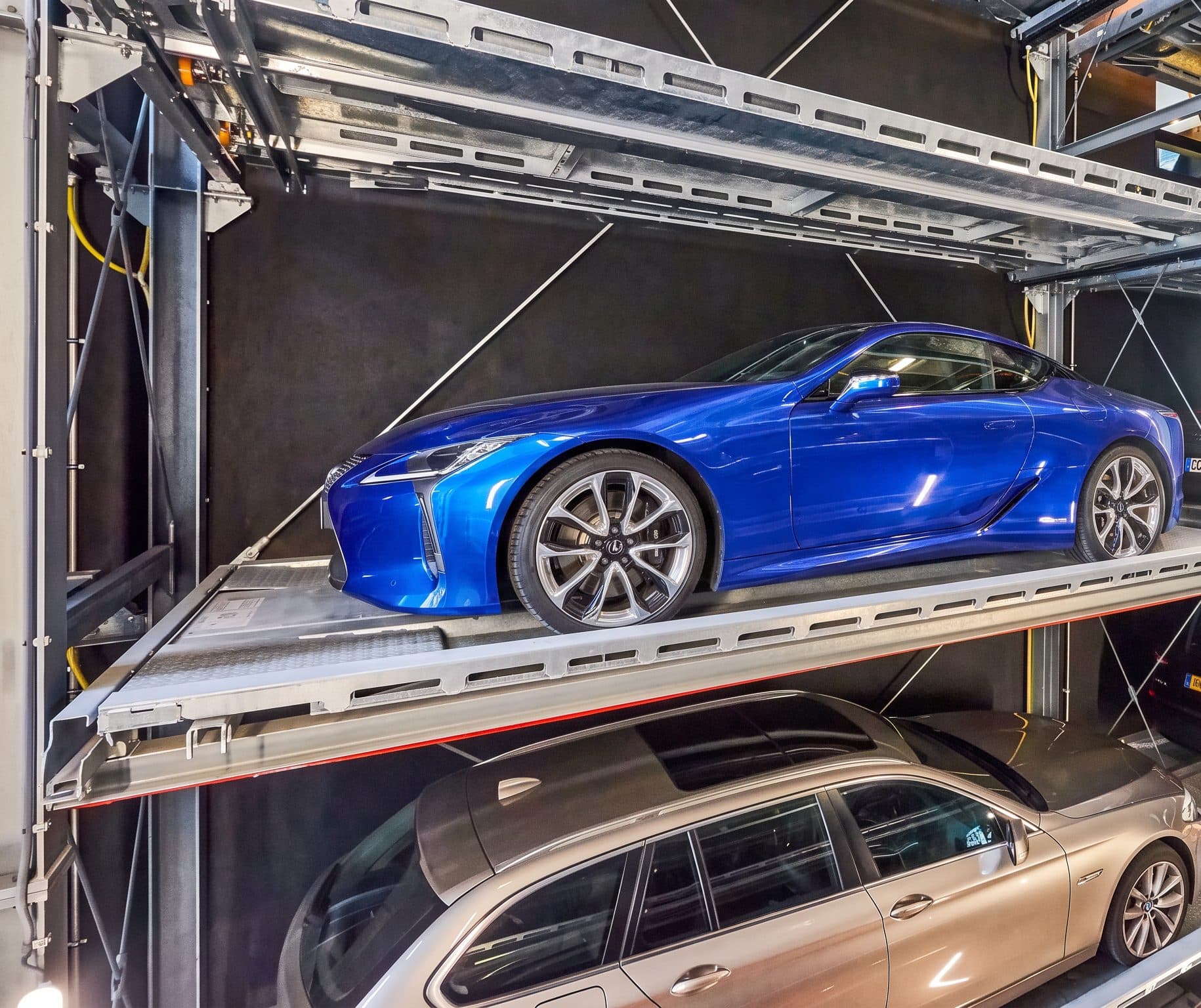 Rayonnage d'acier d'un parking automatique, coupé bleu rangé sur sa palette au-dessus d'un break