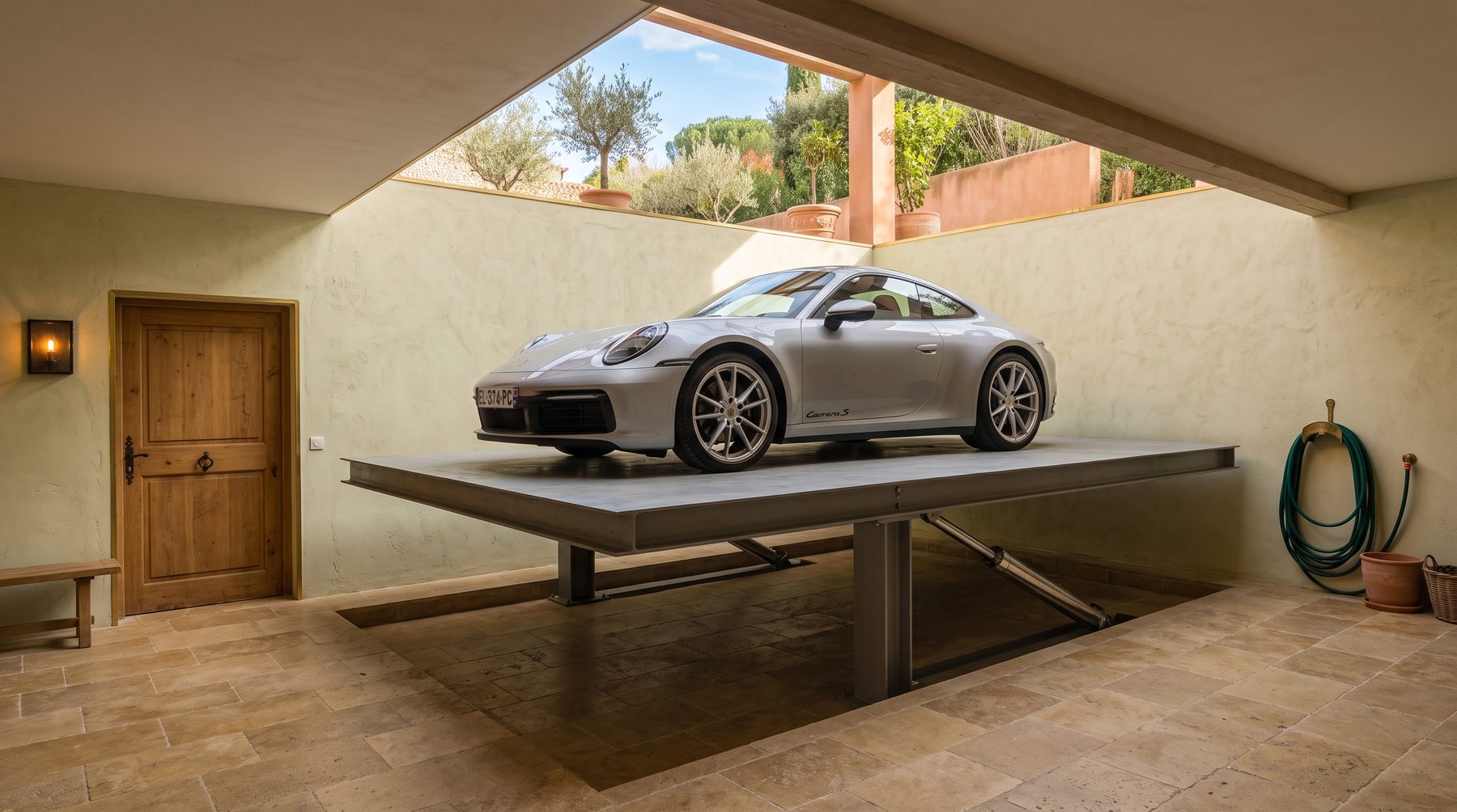 Plateforme de monte-voiture à mi-course dans le garage enterré d'une villa, vérins et colonnes de guidage visibles sous le plateau